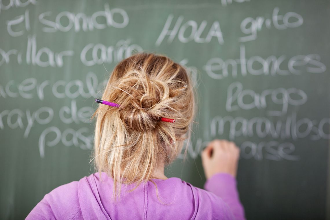 Spanischkurs, Frau schreibt mit Kreide an eine Tafel